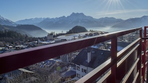 Une ville de montagne aux sommets enneigés, sous un ciel dégagé, où le soleil brille de mille feux.