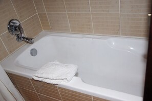 Una bañera blanca con un grifo cromado y una toalla blanca al lado.