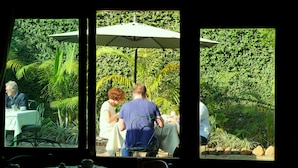A dining area with tables and chairs, surrounded by lush greenery. - Gorillas City Centre Hotel (Kigali)