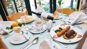 A table set for a meal with plates of food, glasses of wine, and a bottle of wine. - Gorillas City Centre Hotel (Kigali)