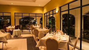Un restaurante con mesas dispuestas para comer, amplias ventanas y vistas de la ciudad.