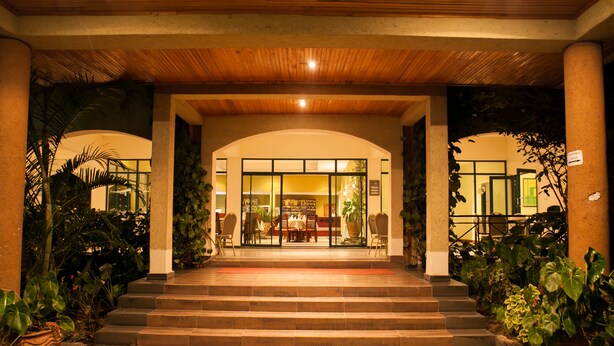Entrada de un hotel con techo de madera, puertas de cristal y escalones que conducen a un comedor.