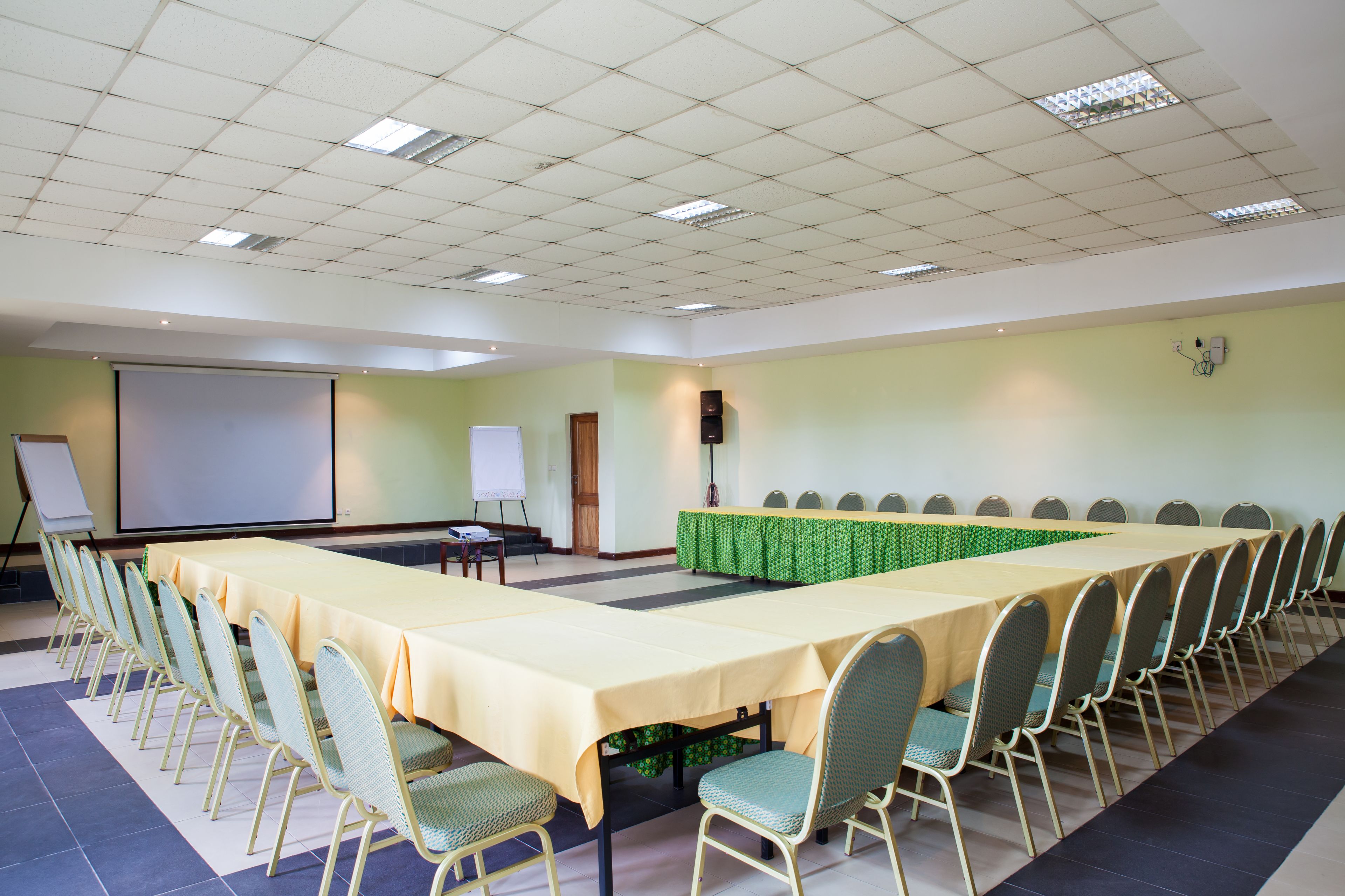 A conference room with a long table, chairs, a projector screen, and a whiteboard.