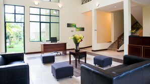 Eine großzügige Lobby mit hohen Decken, großen Fenstern und einer Treppe, die in eine obere Etage führt.