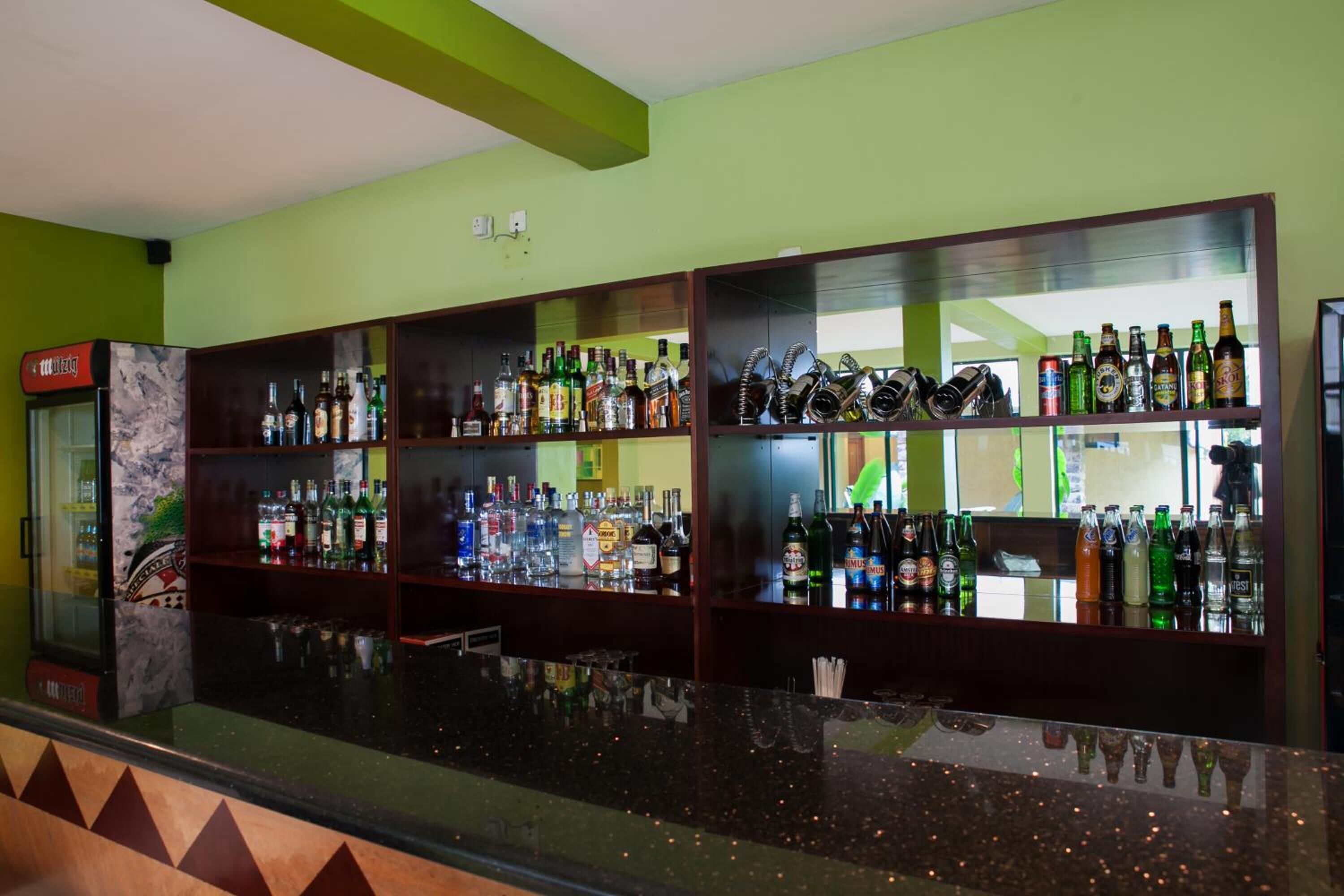 A bar area with shelves of various liquor bottles and glasses.