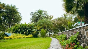 Ein gepflegter Garten mit üppiger Vegetation und verschiedenen Bäumen, durch den ein Kiesweg führt.