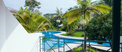 A pool area with a curved design, surrounded by lush greenery and palm trees.