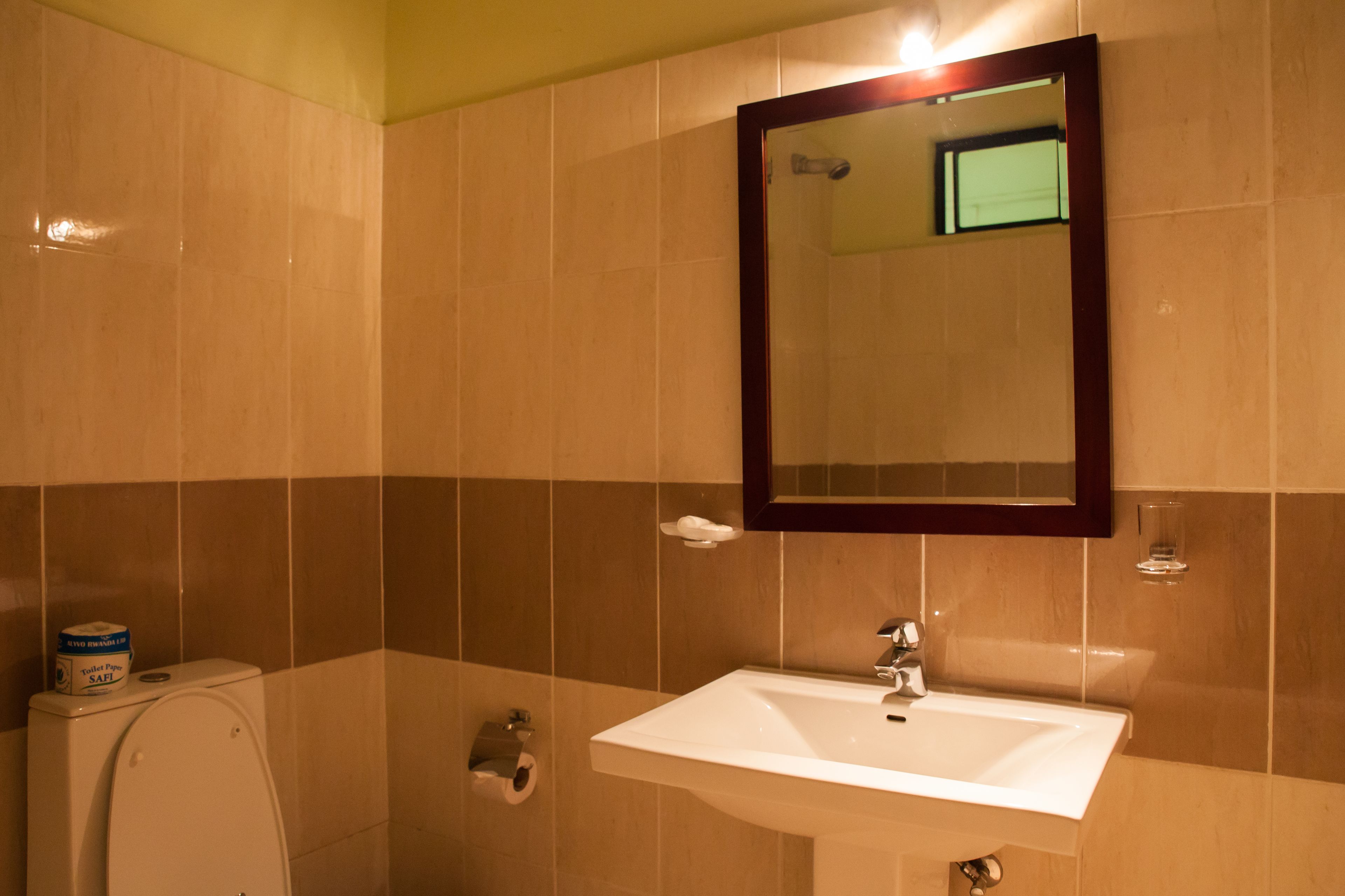 Et badeværelse med toilet, håndvask og spejl.