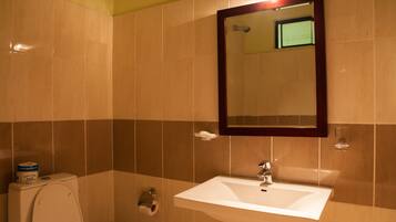 Et badeværelse med toilet, håndvask og spejl.