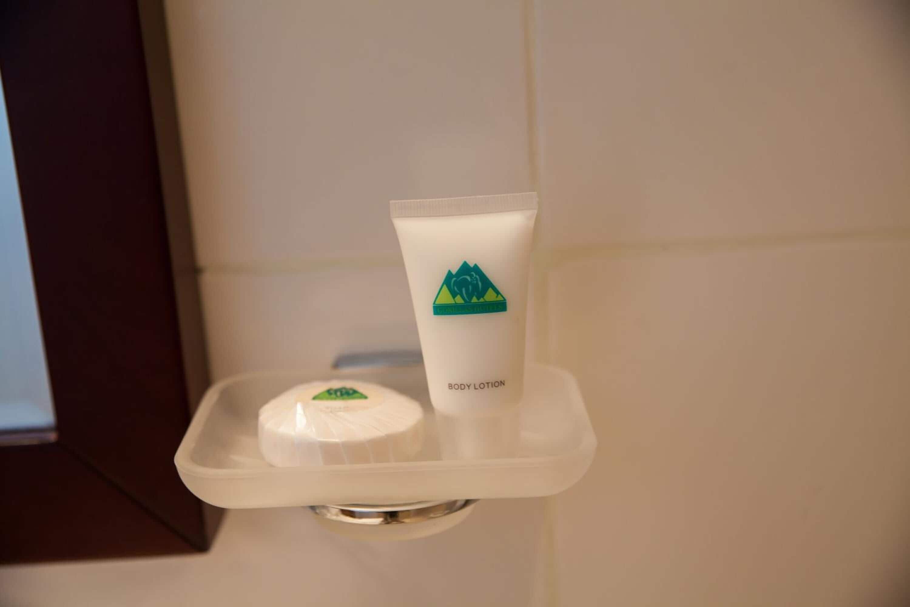 A bathroom with a white sink, a soap dish, and a tube of body lotion on a white tray.
