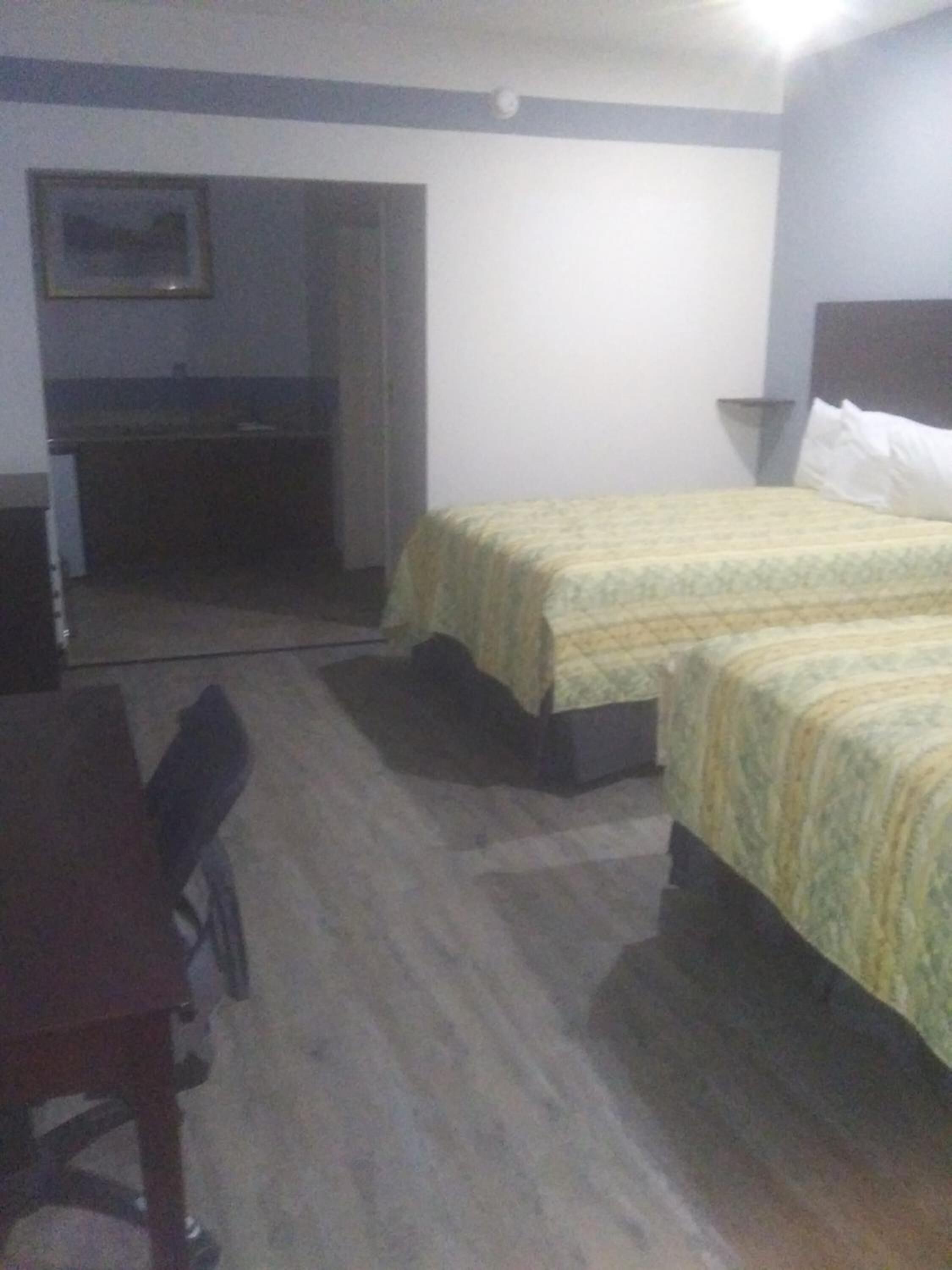 Een hotelkamer met twee bedden, een bureau en een kleine kitchenette.