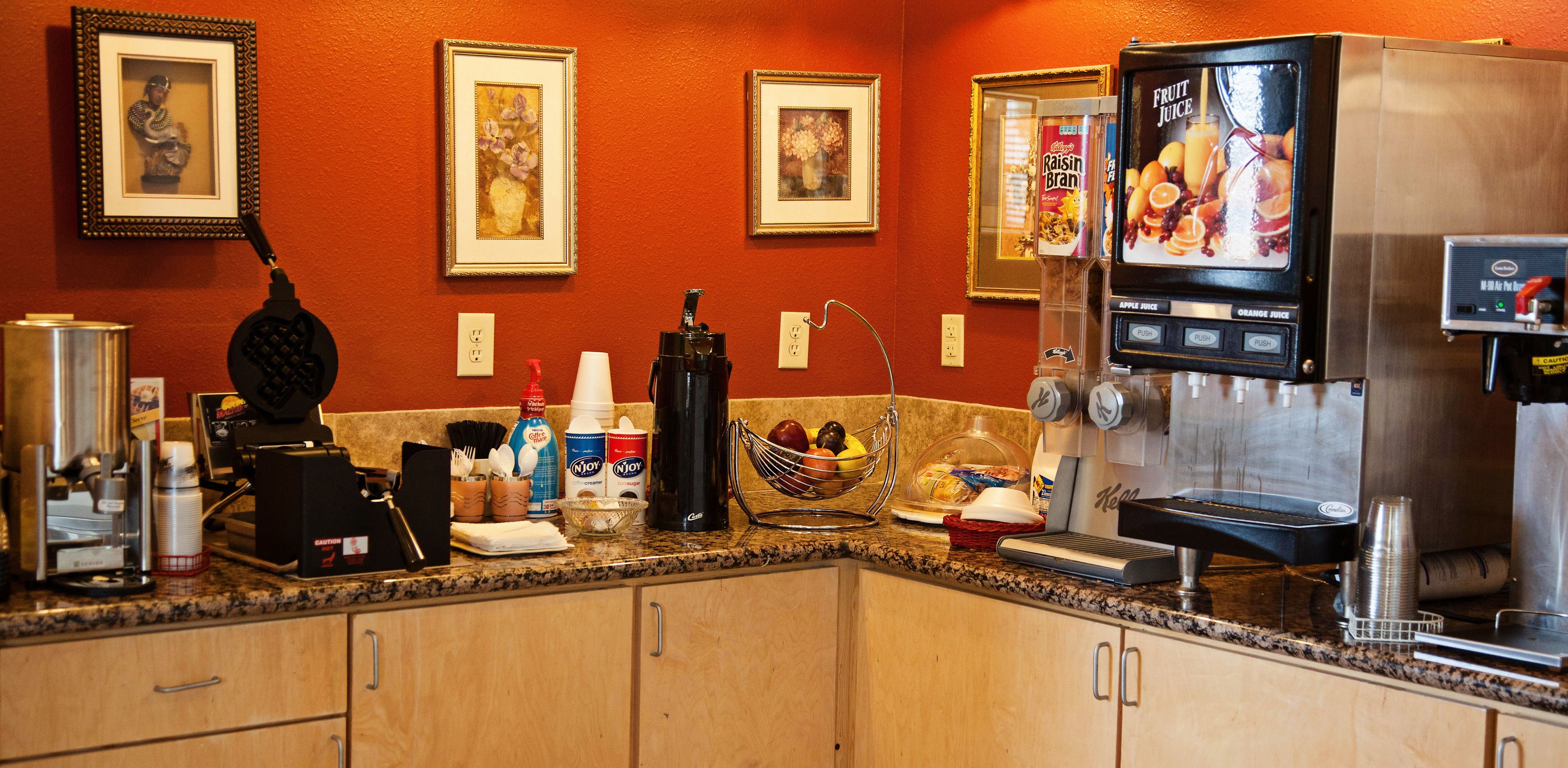 A kitchen with a coffee machine, a juice dispenser, and various kitchen appliances.