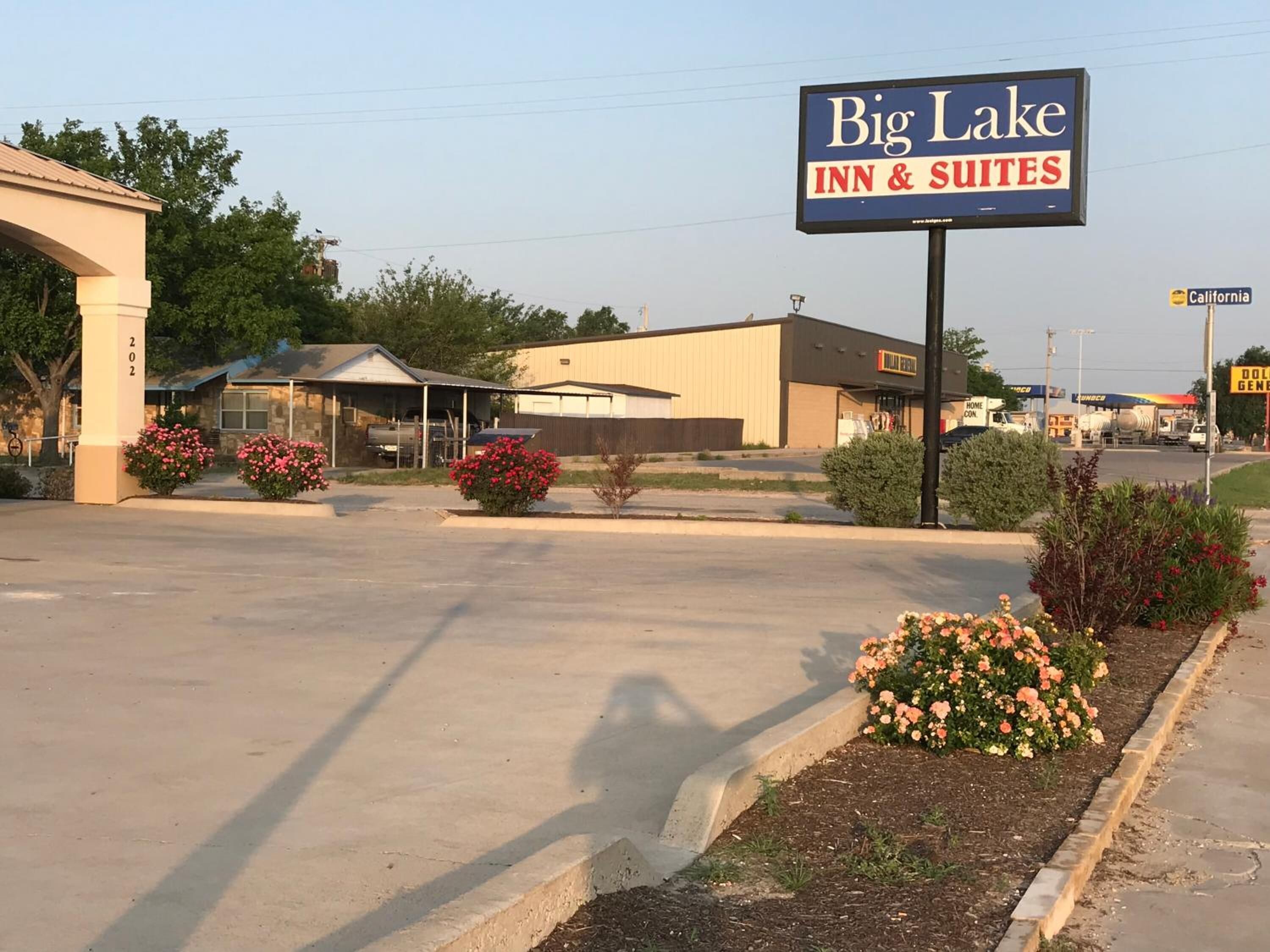 A Big Lake Inn & Suites sign with a parking lot and a building in the background.