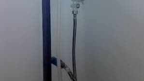 A compact, white water heater unit mounted on a wall, with a control panel and a hose attached. - Funky Fish Hostel (Ko Lanta)