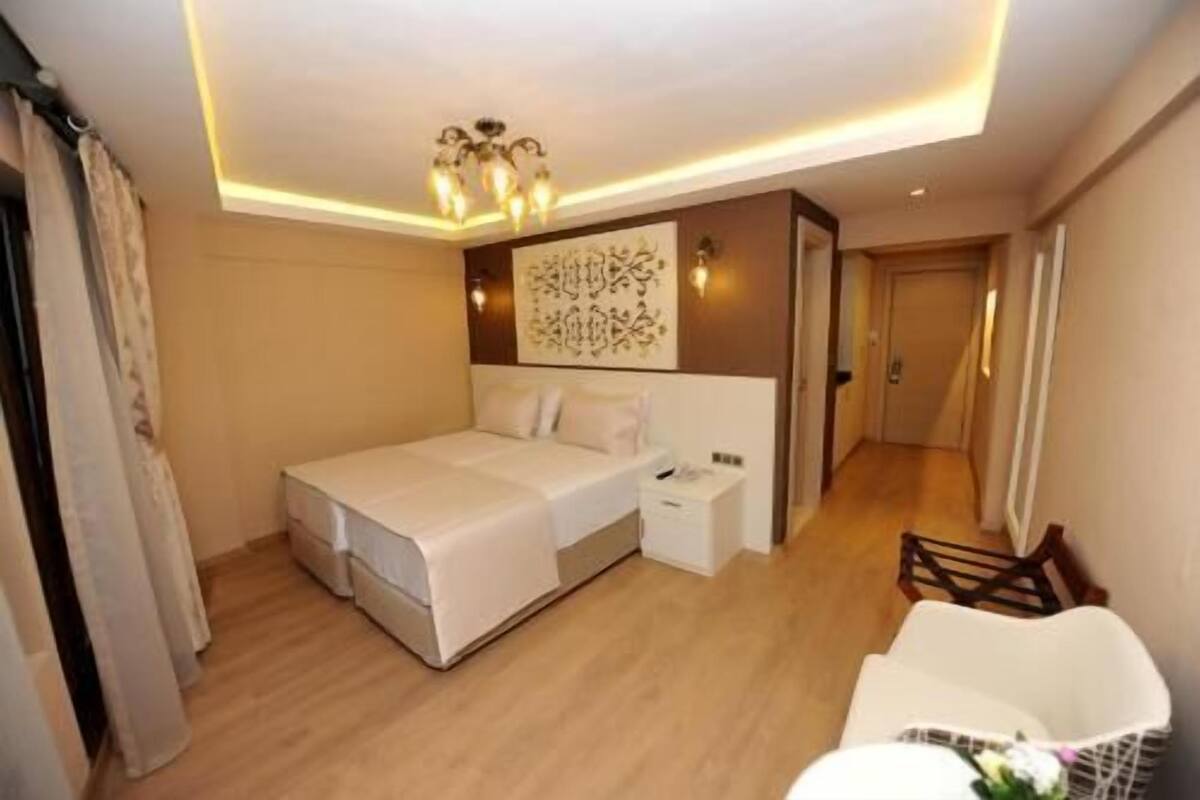 A hotel room with a bed, bedside table, and a wall-mounted artwork.
