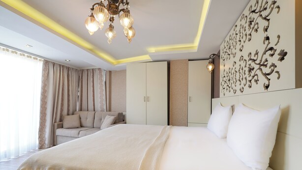 A modern bedroom with a large bed, a sofa, and a decorative wall piece.