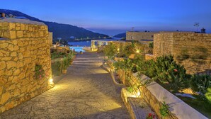 Un sendero de piedra que conduce a una piscina con vistas al mar y colinas.