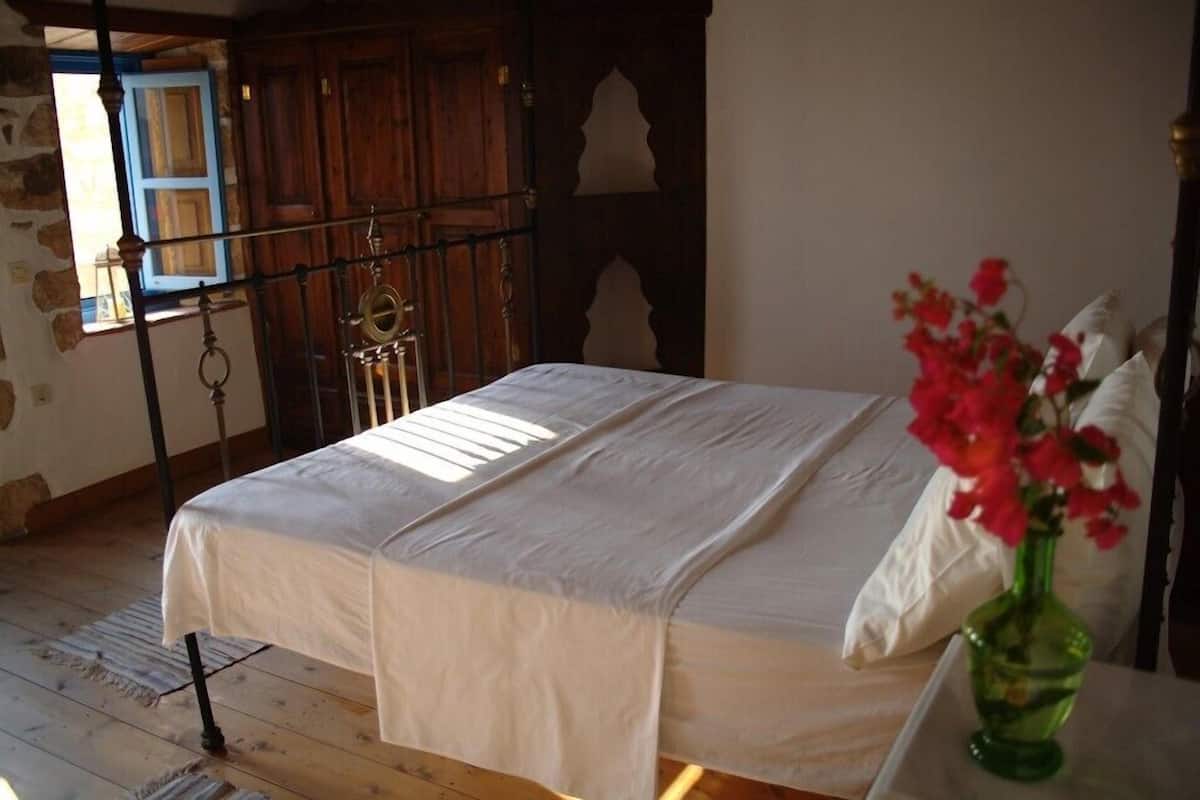 Een slaapkamer met een bed, een groene vaas met bloemen en houten meubels.