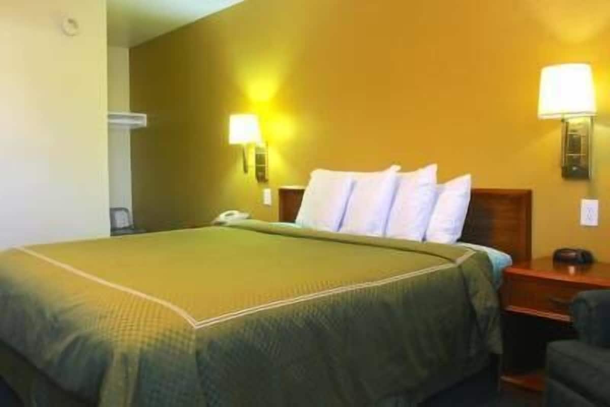 A hotel room with a bed, nightstands, and wall-mounted lamps.
