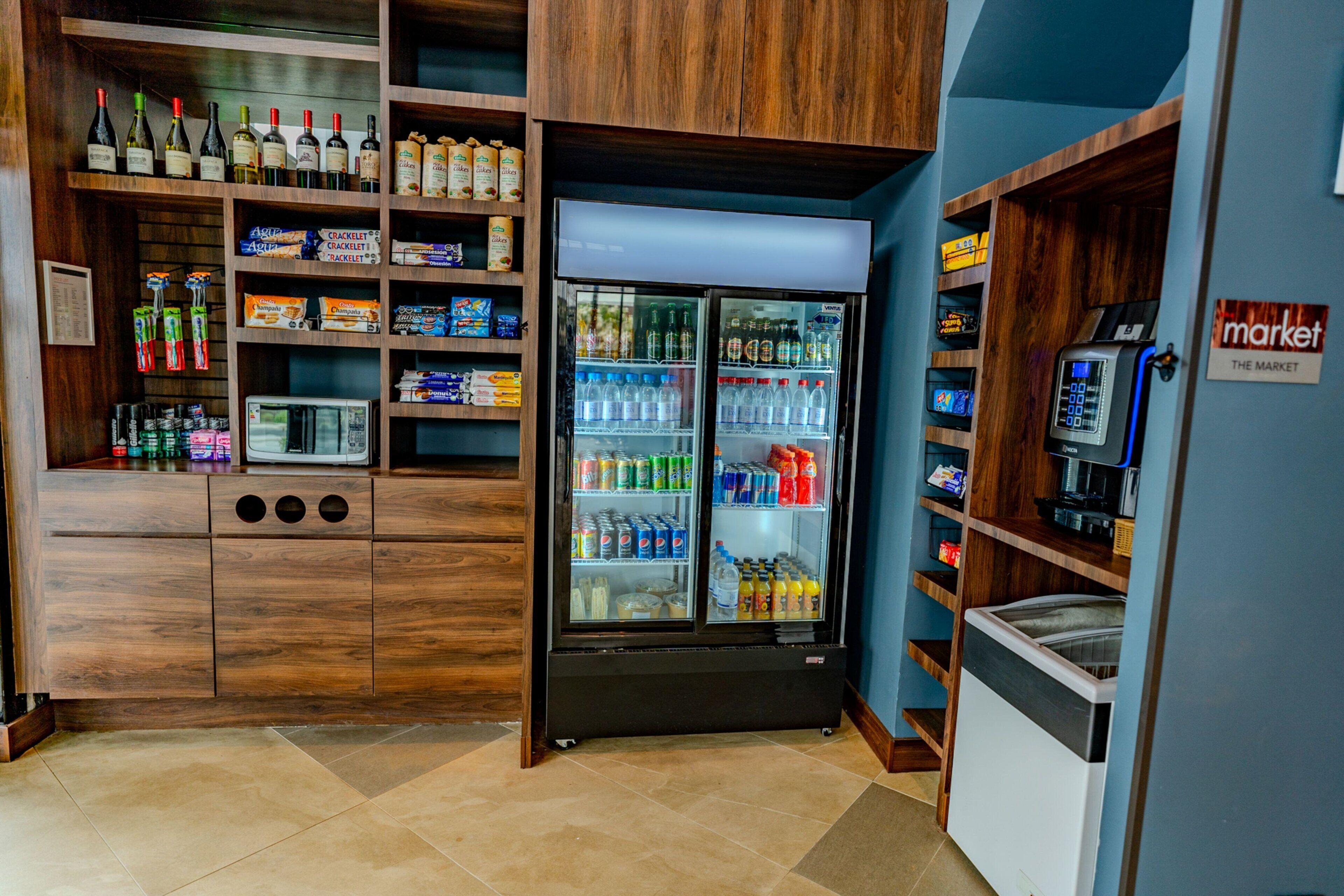 A kitchenette with a refrigerator stocked with beverages, a coffee machine, and various food items.