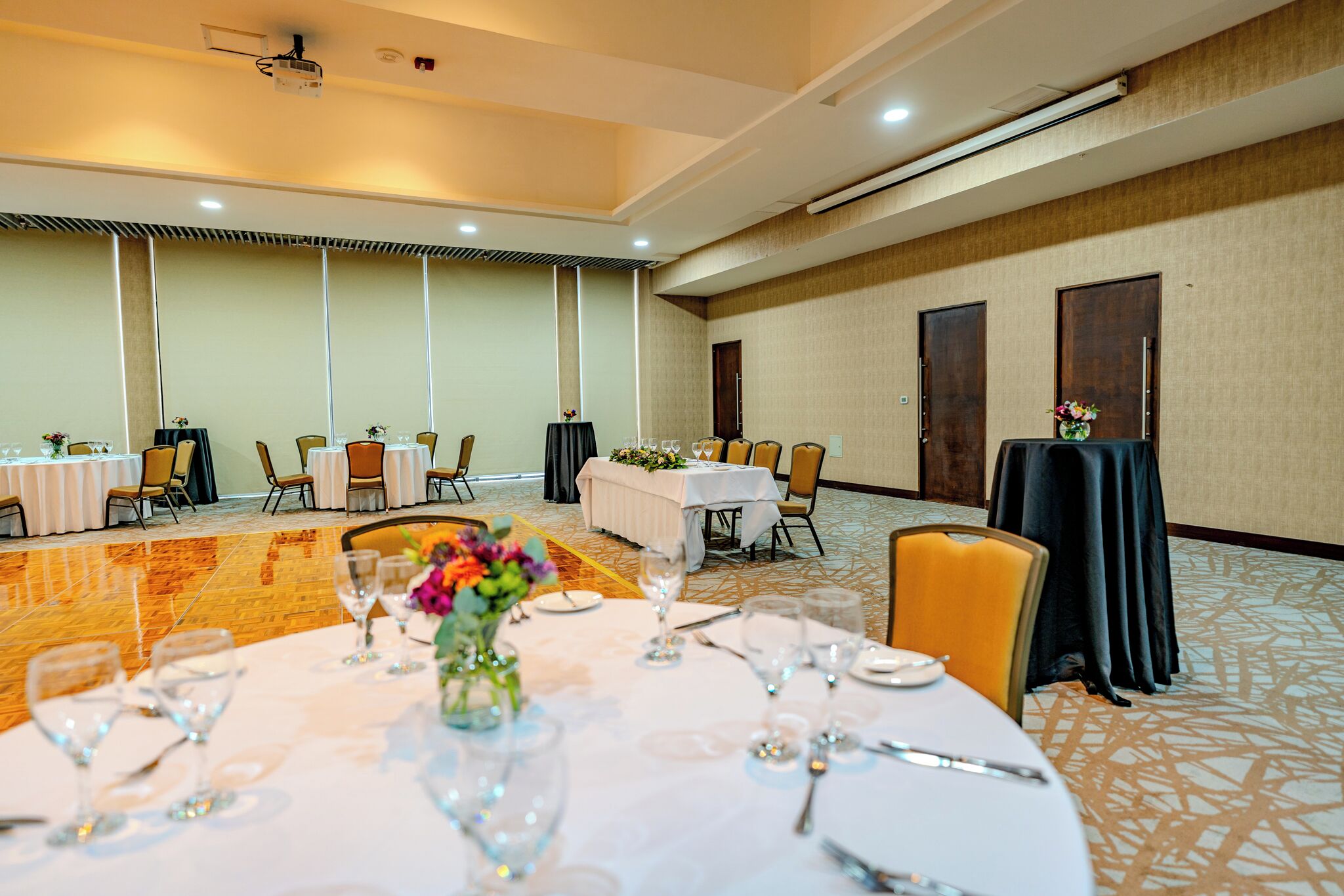 Un salón de conferencias con mesas redondas, sillas y un proyector.