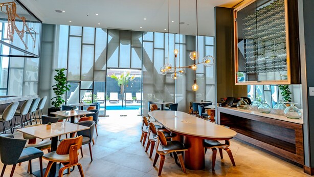 Un área de comedor moderna con una gran mesa ovalada, varias sillas e iluminación colgante.