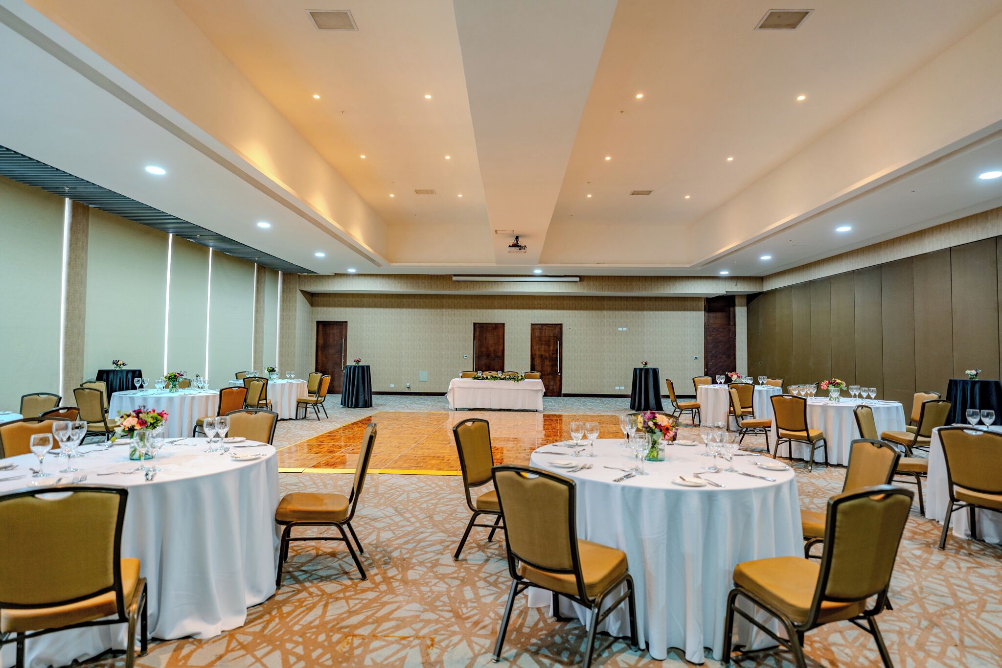 A large conference room with round tables and chairs, a stage, and a carpeted floor.