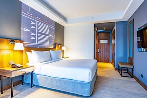 Ein modernes Hotelzimmer mit einem großen Bett, Nachttischlampen, einem Holzkopfschild, einer Bank und einem großen abstrakten Wandbild.