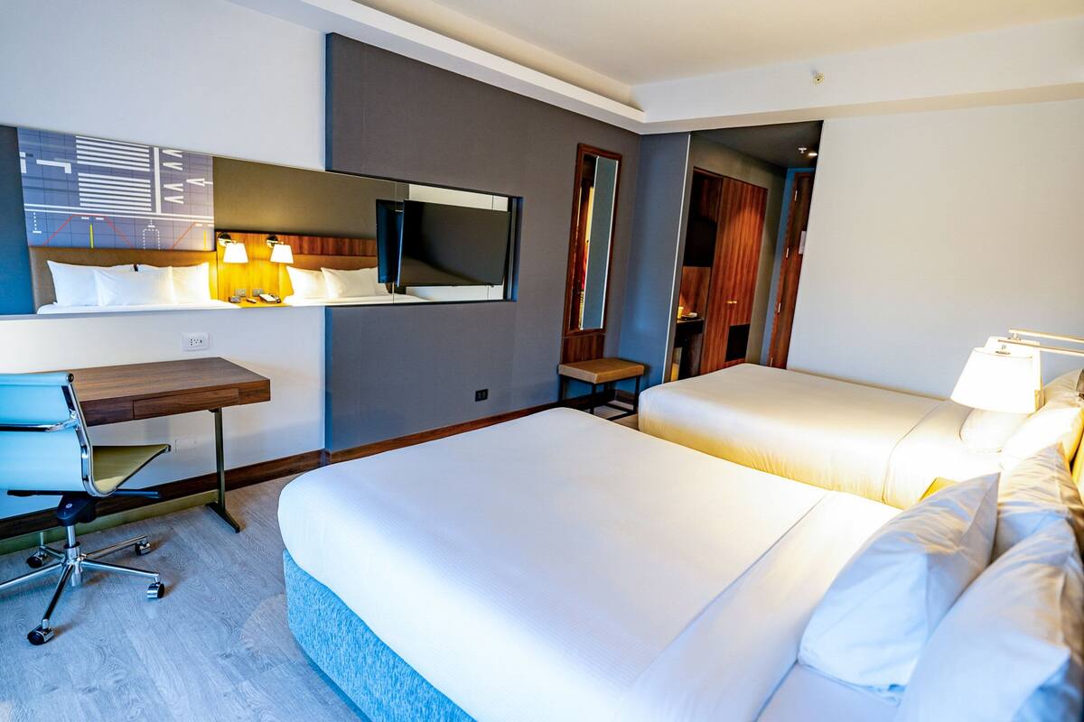 Een hotelkamer met twee bedden, een bureau en een stoel.