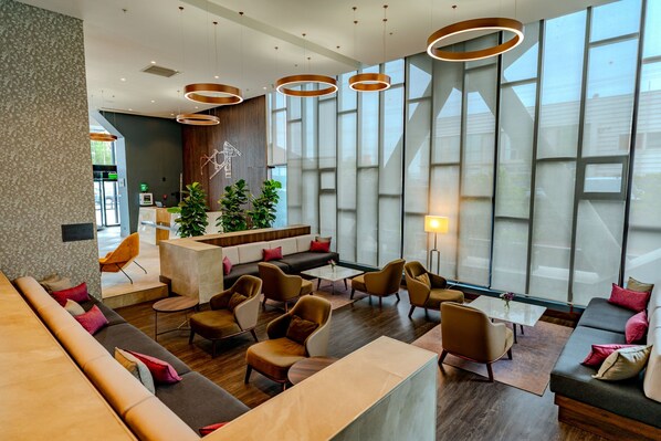 Eine moderne Lobby mit einer Rezeption, Sitzbereichen und großen Fenstern.