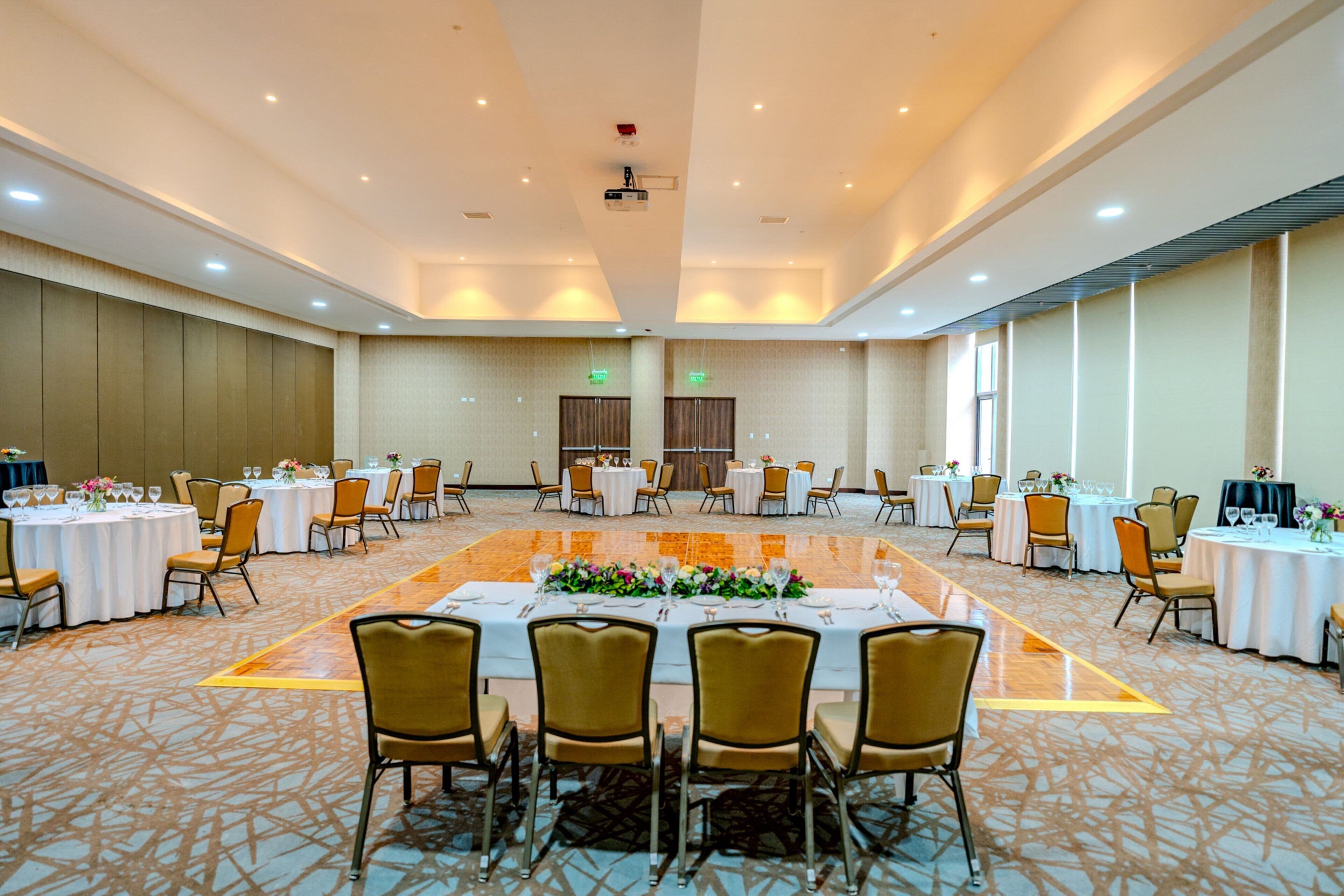 A large banquet hall with round tables set for dining, equipped with chairs and table settings.