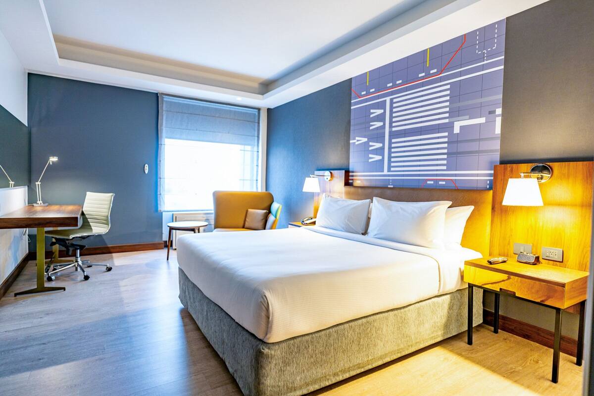 Een hotelkamer met een groot bed, een bureau, een stoel en een kaart aan de muur.