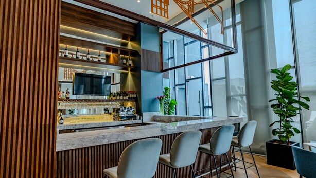 Un área de bar moderna con un muro de acento de madera, una encimera de mármol y taburetes de bar.