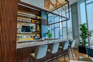 Un área de bar moderna con un muro de acento de madera, una encimera de mármol y taburetes de bar.