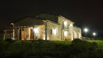 Uma casa de pedra com varanda coberta e área de estar ao ar livre.