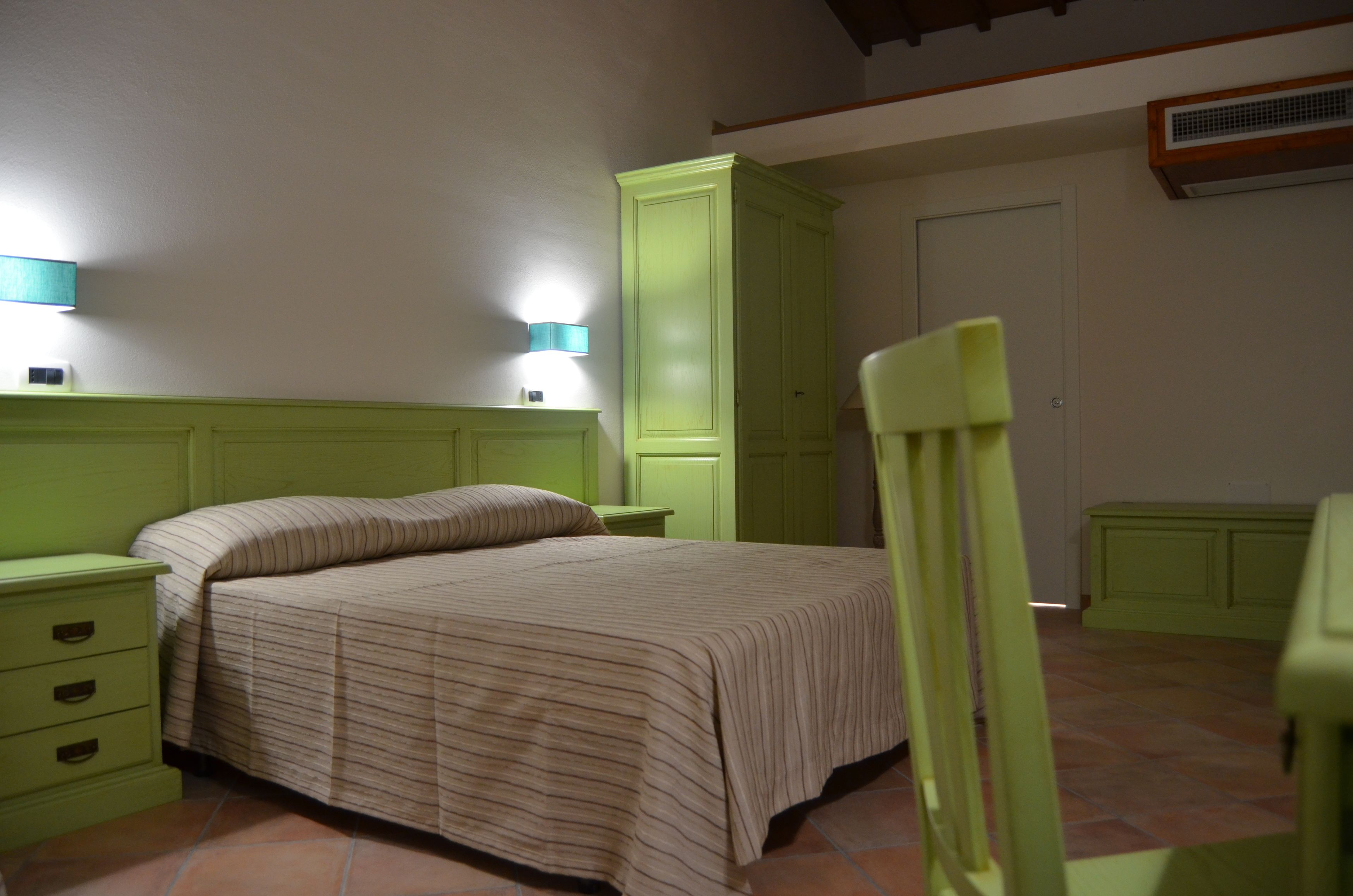 Ein Schlafzimmer mit einem Bett, Nachttischen, einem Kleiderschrank und einem Sessel.