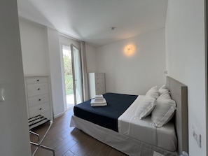 A bedroom with a bed, a dresser, a radiator, and a window with curtains. - Hotel Riva e Mare (Rimini)