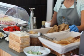 A buffet setup with various food items, including sandwiches, tomatoes, and a salad bowl. - Hotel Riva e Mare (Rimini)