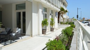 Un hotel moderno con un área de estar exterior techada, plantas en macetas y un balcón con barandilla.