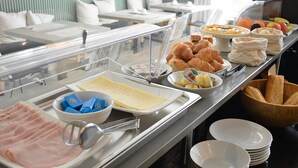 Un bufé con diversas opciones de comida, incluyendo jamón, pasteles y frutas.