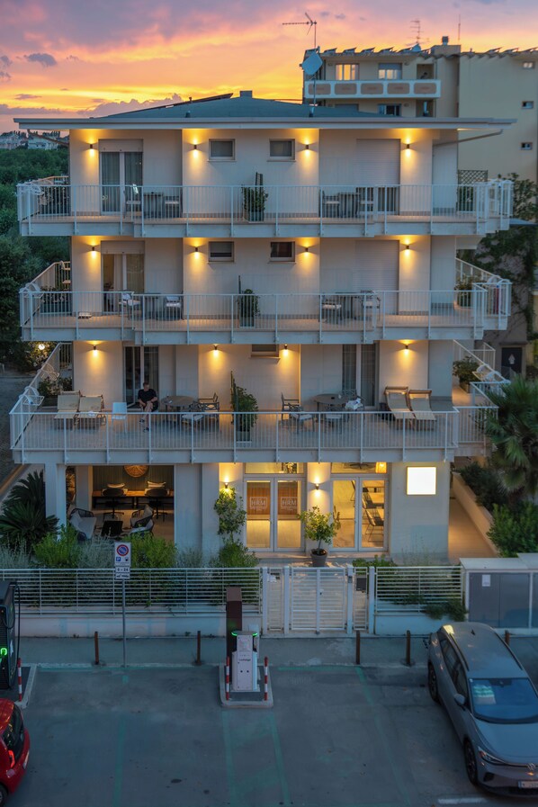 A multi-story building with balconies, outdoor seating, and a gated entrance. - Hotel Riva e Mare (Rimini)