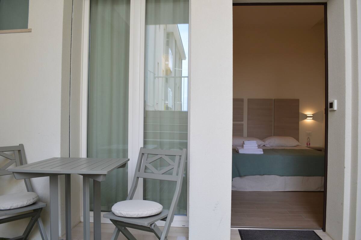 A small room with a bed, a table, and two chairs.