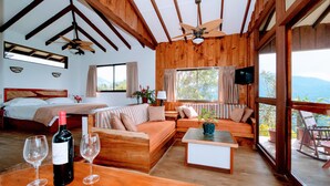 A spacious room with a wooden ceiling, a bed, a sofa, a dining table, and a balcony with a view. - Santa Juana Lodge and Nature Reserve (Naranjito)