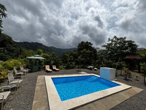 A rectangular pool with a tiled edge, surrounded by a gravel area with lounge chairs and a small table. - Santa Juana Lodge and Nature Reserve (Naranjito)