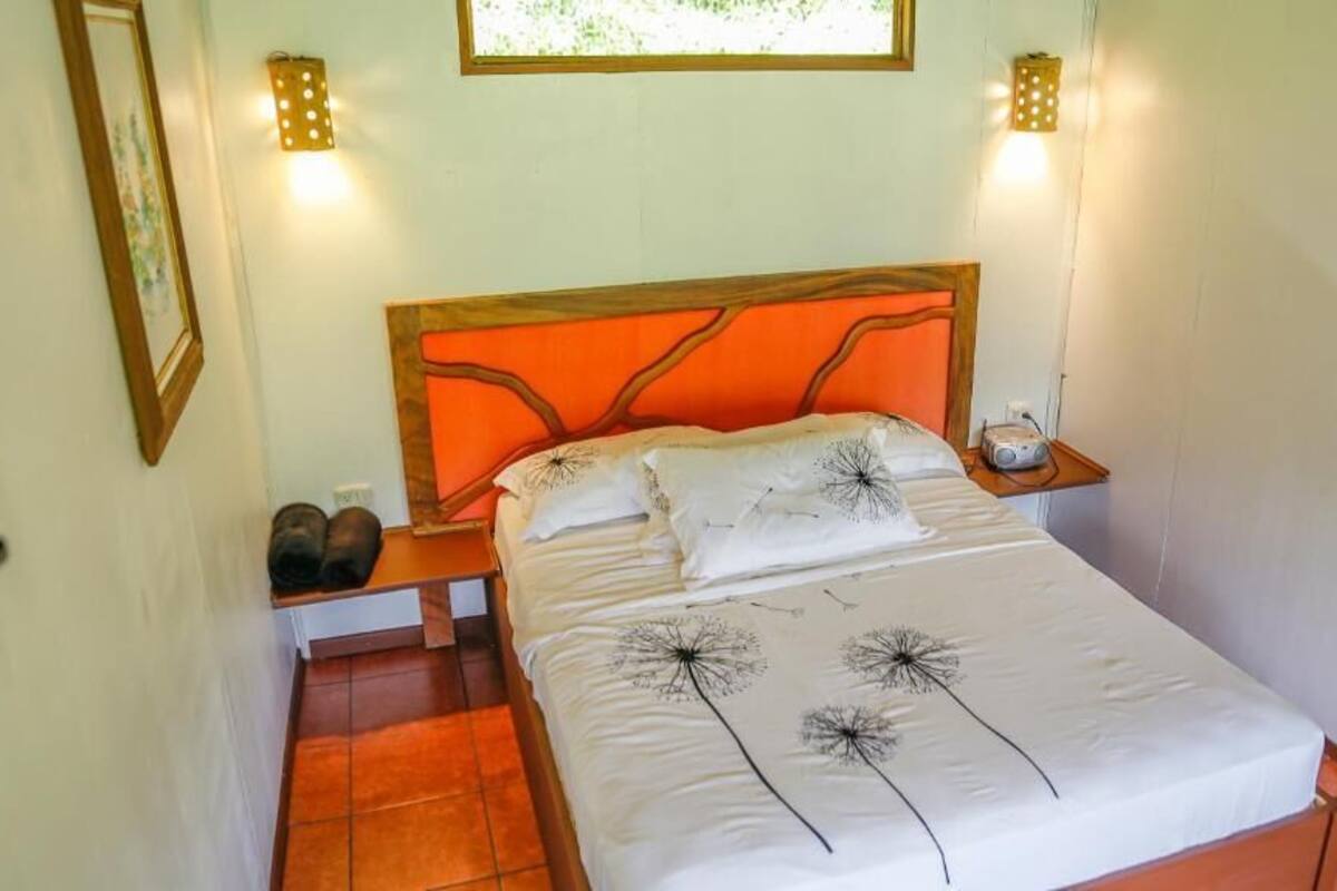 A bed with an orange headboard, white bedding, and a window above.