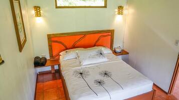 Una cama con cabecera naranja, ropa de cama blanca y una ventana arriba.