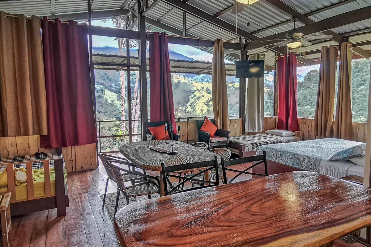 A rustic cabin with a large wooden table, two beds, and a dining area.
