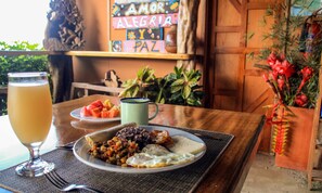 A table with a plate of food, a glass of drink, and a mug. - Santa Juana Lodge and Nature Reserve (Naranjito)