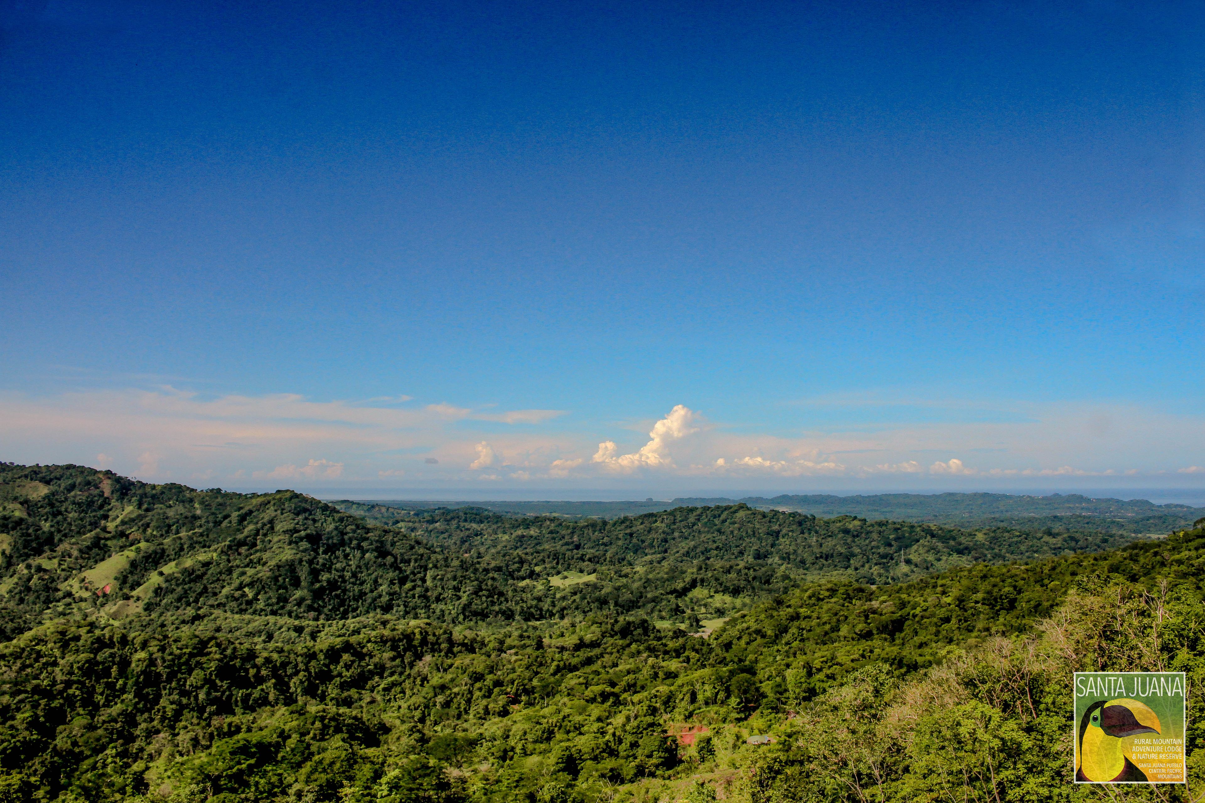 A panoramic view of a lush, green landscape with rolling hills and a clear sky.
