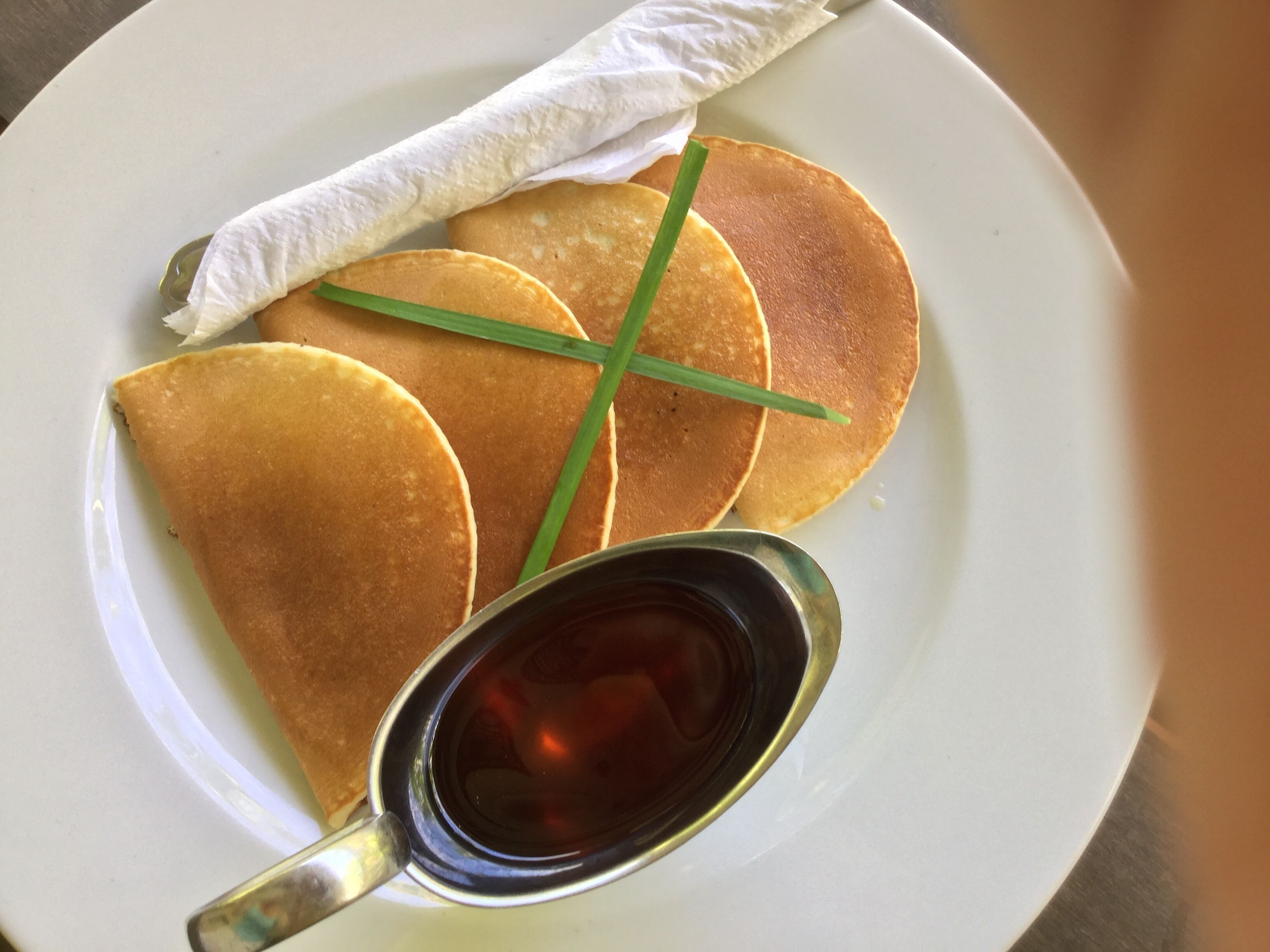 A plate with pancakes, syrup, and a folded napkin.